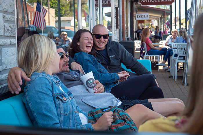 Adult friends enjoy frozen beverages on outdoor patio furniture in downtown historic distric.